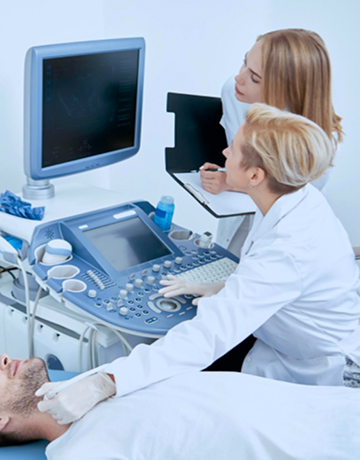 Los técnicos de radiología observan una pantalla de ultrasonido mientras un técnico mueve una sonda alrededor de la tiroides de un paciente